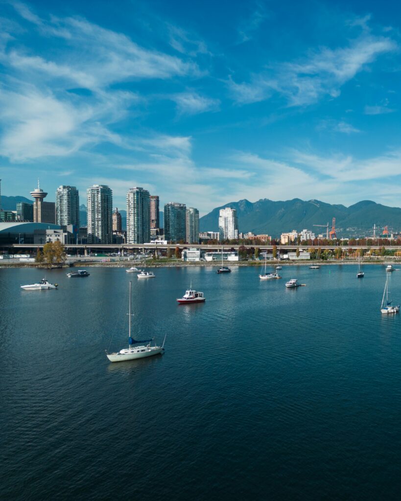 A stunning aerial view of Vancouver Harbor featuring sailboats against a backdrop of the city's skyline and mountains.